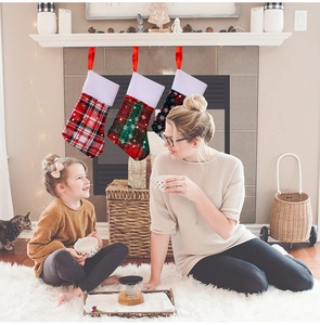 Plaid Christmas stocking cutlery holders and mini gift bags hanging on a cozy fireplace