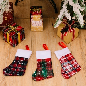 Set of three plaid Christmas stockings with snowflake patterns on wooden floor
