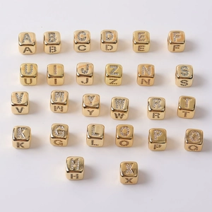 Makro-Detail von 26 goldenen Buchstabenperlen mit Zirkonia-Pflaster für DIY-Schmuck