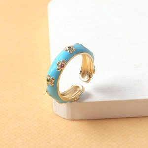 Bague réglable en forme de fleur dorée avec émail bleu et zircons colorés sur bloc blanc