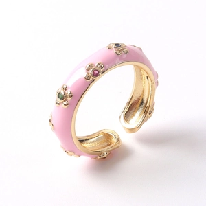 Détail d'une bague ajustable en émail rose avec fleurs dorées et zircons colorés
