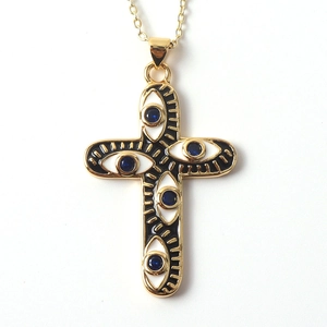 Detailed view of golden cross pendant with evil eye motif and blue stone inlay