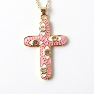 Detail of cross pendant with pink enamel evil eyes and a centered gem on gold chain
