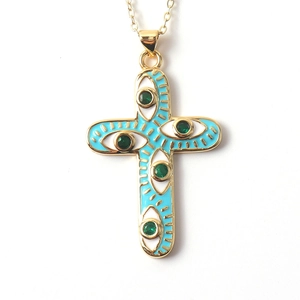 Detail of cross pendant with blue enamel and green zircon evil eye motif in gold
