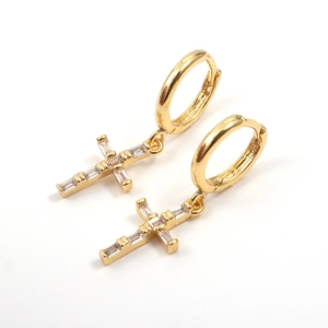 Close-up of gold hoop earrings featuring cross pendants with baguette-cut cubic zirconia