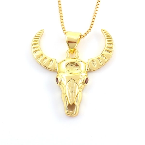 Macro shot of gold bull skull pendant with red gemstone eyes and textured horns