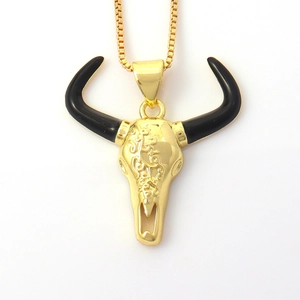 Detail of golden longhorn skull necklace with black horns and ornate floral engravings