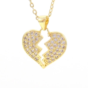 Macro shot of gold broken heart pendant with micro-pave cubic zirconia on a fine chain