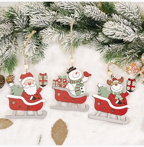 Close-up of wooden ski ornaments with Santa, snowman and deer hanging on frosted pine branch