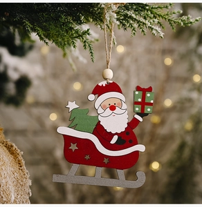Close-up of Santa on a red wooden sleigh ornament hanging from a snowy tree branch