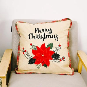 Detail of Merry Christmas pillow cover with red poinsettia and tartan plaid edges