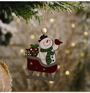 Detailed view of hand-painted snowman on wooden sleigh hanging on a snowy branch