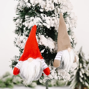 Detail of plush Christmas gnomes with striped arms hanging on a snowy Christmas tree