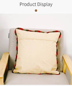Detail view of beige linen pillow cover with red and green plaid edges on armchair