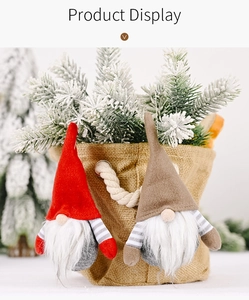 Close-up of Christmas gnome ornaments with striped hats and faux fur beards on pine needles