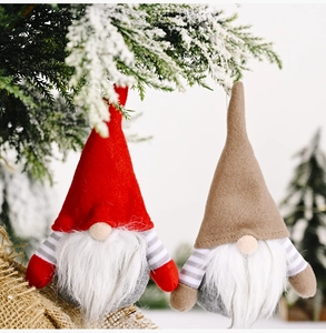Detailed view of red and khaki striped gnome ornaments hanging on a snowy Christmas tree