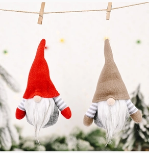 Close-up of red and brown Christmas gnomes with striped arms hanging on twine