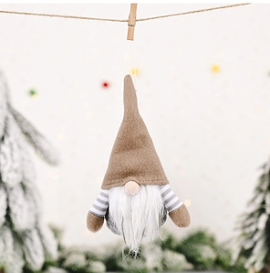 Detail of Christmas striped gnome ornament hanging on rope with festive bokeh background