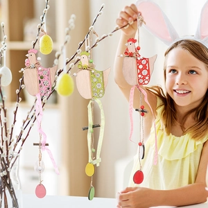 Close-up of a girl hanging colorful wooden Easter rooster ornaments on willow branches