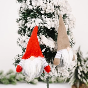 Christmas striped gnome ornaments with plush white beards hanging on snowy pine trees