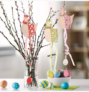 Detail of wooden Easter hen pendants with plaid ribbons and beads hanging on branches