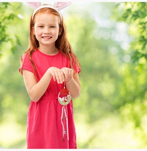 Close-up of wooden Easter egg ornament with rooster design held by a child outdoors