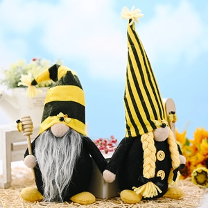 Close-up of handmade bee gnomes with striped hats holding a wooden honey dipper tool