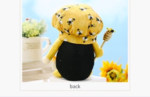 Back view of a yellow bee themed gnome plush holding a wooden honey dipper stick