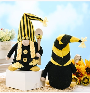 Close-up of handmade bumblebee gnomes with yellow striped hats and wooden honey dippers