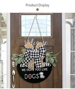 Detail of wooden welcome sign with buffalo plaid bow and greenery on a rustic door