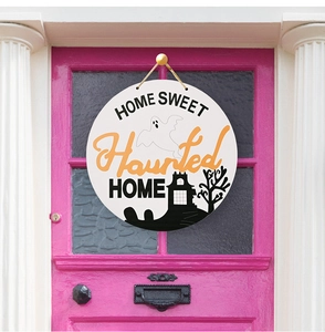 Detail van houten Halloween-deurbordje met Home Sweet Haunted Home op een roze deur