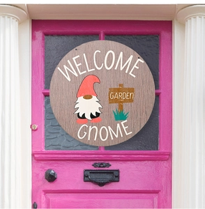 Close-up of circular wooden Welcome Gnome sign hanging on a vibrant pink retro door