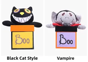 Halloween plush toys in boxes featuring a black cat and vampire with festive Boo patterns