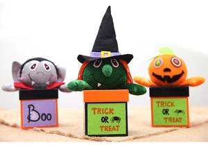 Detail view of plush vampire, witch, and pumpkin dolls in Halloween themed gift boxes