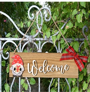 Detail of wooden welcome sign with festive gnome, plaid bow, and 3D lettering on a fence