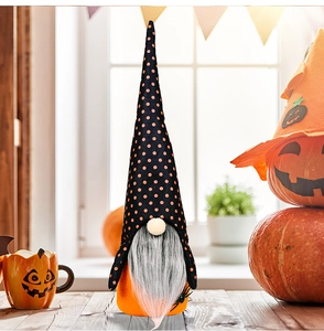 Macro detail of Halloween orange gnome with grey beard on wooden table setting