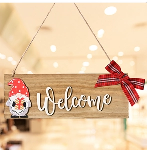 Detail of wooden welcome door sign with gnome figure and red plaid bow decoration