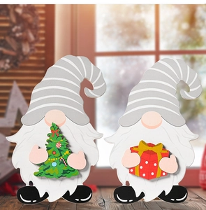 Close-up of two wooden Christmas gnomes with interchangeable parts on a warm desk