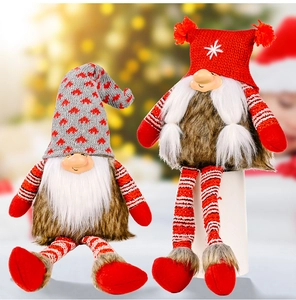Detail of two Christmas gnomes with knitted hats and long legs against a festive tree