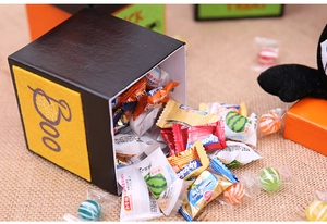 Detail of Halloween cube gift box with Boo text and assorted candies on burlap