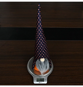 Halloween gnome plush ornament weighing 166.9g on a digital scale with orange polka dots