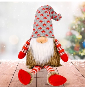 Detail of Christmas gnome with gray knitted heart hat and fuzzy body on wooden surface