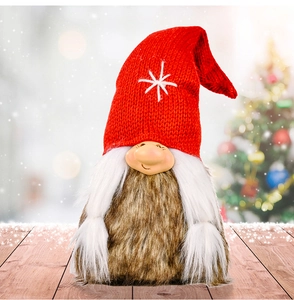 Detail of Christmas gnome plush with red knitted star hat and white braids on wood surface