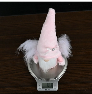 Detalle que muestra el peso de 101,0g de un gnomo de Navidad rosa con alas de plumas