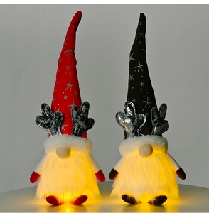 Close-up of lighted Christmas gnomes with silver antlers and knitted hats on a grey base