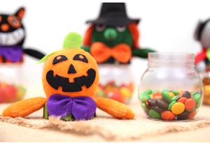 Close-up of Halloween pumpkin candy jar with plush lid and clear container for party decor