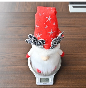 Close-up of a Christmas gnome with antlers on a scale showing a weight of 131.2 grams