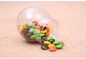 Close-up of colorful candies spilling from a transparent spherical Halloween jar