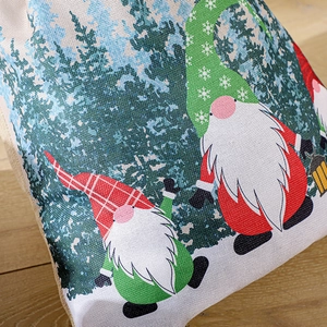 Christmas gnome drawstring gift bag made of rustic linen fabric on wooden background