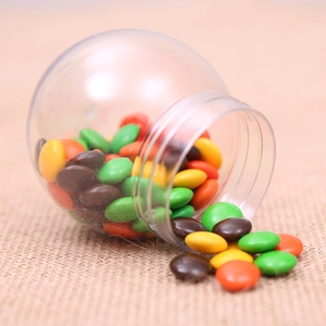 Creative sphere Halloween candy jar with colorful chocolate beans on rustic burlap background